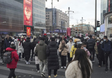 People cross a road at a shopping area in Beijing on Tuesday, Feb. 4, 2025. (AP Photo/Aaron Favila)