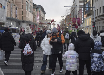 People cross a road at a shopping area in Beijing on Tuesday, Feb. 4, 2025. (AP Photo/Aaron Favila)