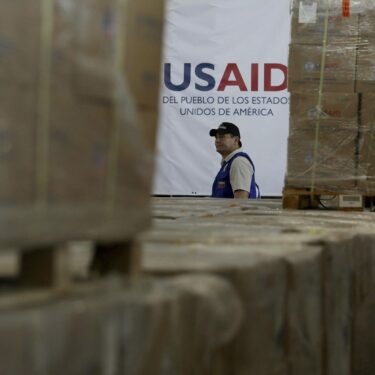 FILE - A man walks past boxes of USAID humanitarian aid at a warehouse at the Tienditas International Bridge on the outskirts of Cucuta, Colombia, Feb. 21, 2019, on the border with Venezuela. (AP Photo/Fernando Vergara, File)