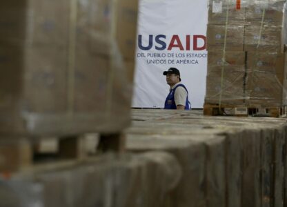 FILE - A man walks past boxes of USAID humanitarian aid at a warehouse at the Tienditas International Bridge on the outskirts of Cucuta, Colombia, Feb. 21, 2019, on the border with Venezuela. (AP Photo/Fernando Vergara, File)