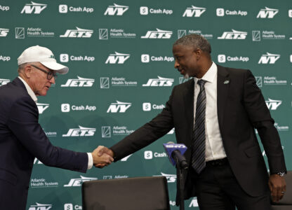 FILE - New York Jets new head coach Aaron Glenn, right, shakes hands with team owner Woody Johnson, left, during a news conference at the NFL football team's training facility Jan. 27, 2025, in Florham Park, N.J. (AP Photo/Adam Hunger,File)