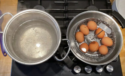 This photo provided by researchers in February 2025 shows two pots, one with boiling water, left, and the other with a basket of eggs in lukewarm water, in a new method of boiling eggs dubbed 