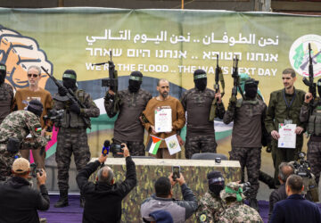 Israeli captives, from left to the right, Ohad Ben Ami, Eli Sharabi and Or Levy, who have been held hostage by Hamas in Gaza since Oct. 7, 2023, are escorted by Hamas fighters on a stage before being handed over to the Red Cross in Deir al-Balah, central Gaza Strip, Saturday, Feb. 8, 2025. (AP Photo/Abdel Kareem Hana)