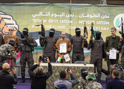 Israeli captives, from left to the right, Ohad Ben Ami, Eli Sharabi and Or Levy, who have been held hostage by Hamas in Gaza since Oct. 7, 2023, are escorted by Hamas fighters on a stage before being handed over to the Red Cross in Deir al-Balah, central Gaza Strip, Saturday, Feb. 8, 2025. (AP Photo/Abdel Kareem Hana)