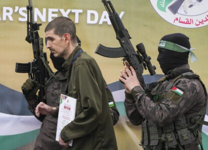 Israeli captive Or Levy, who has been held hostage by Hamas in Gaza since October 7, 2023, is escorted by Hamas fighters before being handed over to the Red Cross in Deir al-Balah, central Gaza Strip, Saturday Feb. 8, 2025. (AP Photo/Abdel Kareem Hana)