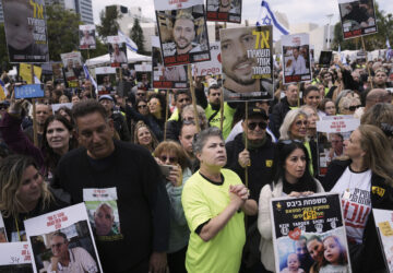 People holding posters with photos of Israelis hostages Eli Sharabi, Or Levy and Ohad Ben Ami, gather at the so-called 