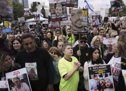 People holding posters with photos of Israelis hostages Eli Sharabi, Or Levy and Ohad Ben Ami, gather at the so-called 