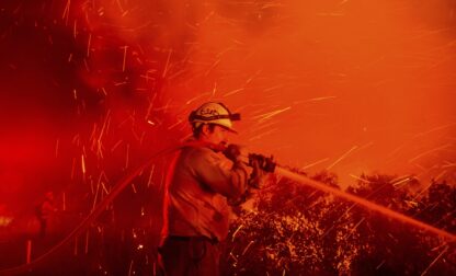 FILE - Firefighter Joshua Cari sprays water while battling the Lilac Fire near the Bonsall community of San Diego County, Calif., Jan. 21, 2025. (AP Photo/Noah Berger, File)