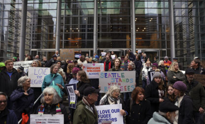 People hold signs as they gather outside the U.S. District Court after a federal judge blocked President Donald Trump's effort to halt the nation's refugee admissions system Tuesday, Feb. 25, 2025, in Seattle. (AP Photo/Ryan Sun)