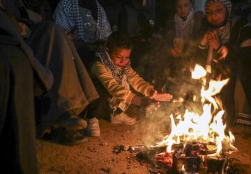 A boy warms up as families and friends of Palestinian prisoners to be released from Israeli prison wait around a bonfire for their arrival in Khan Younis, southern Gaza Strip, late Wednesday Feb. 26, 2025. (AP Photo/Jehad Alshrafi)