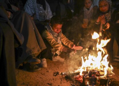 A boy warms up as families and friends of Palestinian prisoners to be released from Israeli prison wait around a bonfire for their arrival in Khan Younis, southern Gaza Strip, late Wednesday Feb. 26, 2025. (AP Photo/Jehad Alshrafi)