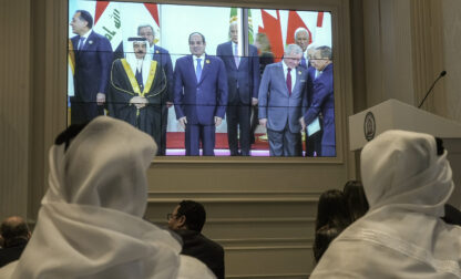 Journalists watch a screen displaying Egyptian President Abdel Fattah el-Sissi, center, with Arab Leaders, at the press center hall of the emergency Arab summit at Egypt's New Administrative Capital, just outside Cairo, Tuesday, March 4, 2025. (AP Photo/Amr Nabil)