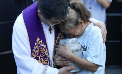 Filipino Catholic priest Flavie Villanueva, left, consoles Melinda Lafuente, as she holds the urn containing the remains of her son Angelo, during an interment ceremony for victims of extrajudicial killings, at the 