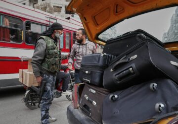 A fighter from the Druze Rijal al-Karameh militia talks to a driver while looking through his car at a checkpoint in the town of Jaramana, in the southern outskirts of Damascus, Syria, March 3, 2025. (AP Photo/Omar Sanadiki)