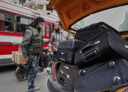 A fighter from the Druze Rijal al-Karameh militia talks to a driver while looking through his car at a checkpoint in the town of Jaramana, in the southern outskirts of Damascus, Syria, March 3, 2025. (AP Photo/Omar Sanadiki)