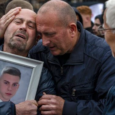 Dragi Stojanov, left, cries holding a photograph of his son Tomche Stojanov, one of the victims of a massive nightclub fire, during a vigil joined by hundreds in the town of Kocani, North Macedonia, Monday, March 17, 2025. (AP Photo/Visar Kryeziu)