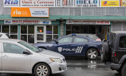 A police car patrols a street in front of a liquor store in Barrio Obrero, San Juan, Puerto Rico, Friday, March 14, 2025. (AP Photo/Alejandro Granadillo)